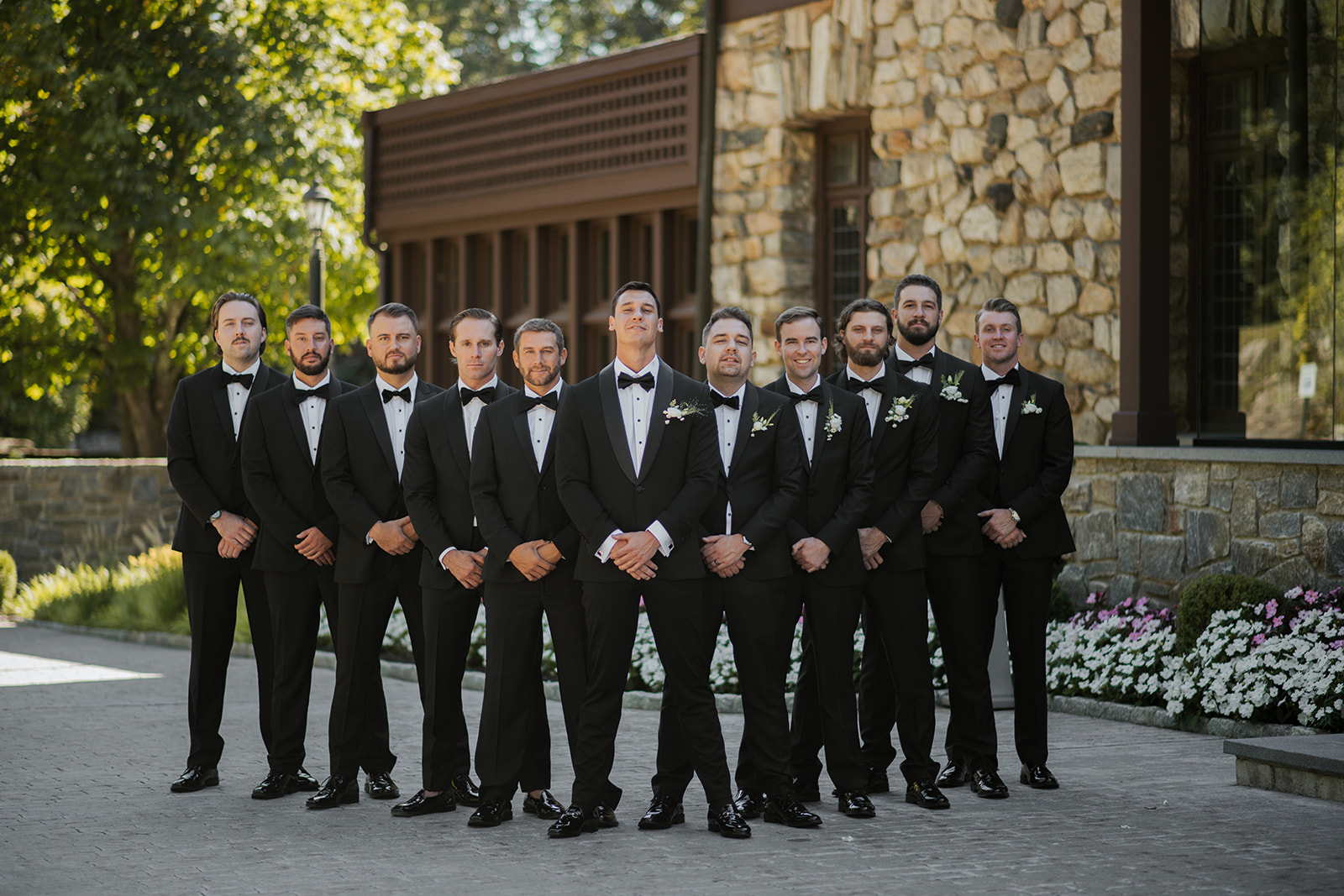 Groom standing confidently with his groomsmen in front of the stone facade of Le Chateau.